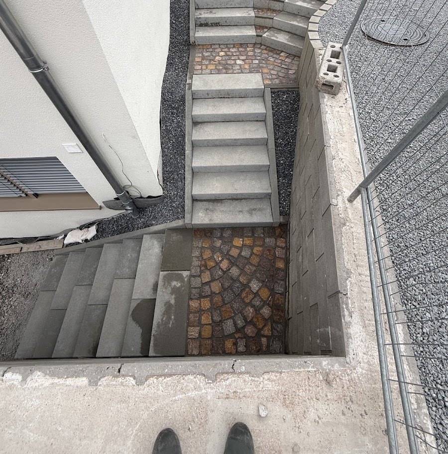 Neu gesetzte Betonblockstufen-Außentreppe mit Winkelstützmauer