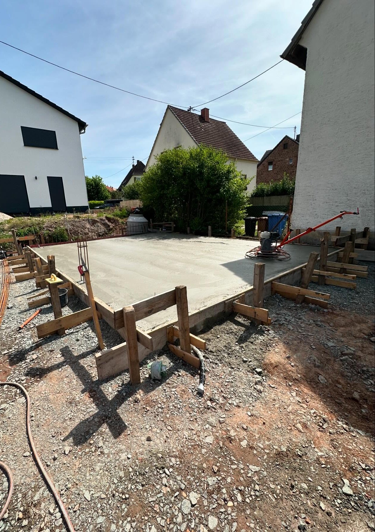 Frisch betonierte und flügelgeglättete Bodenplatte in massiver Holzschalung