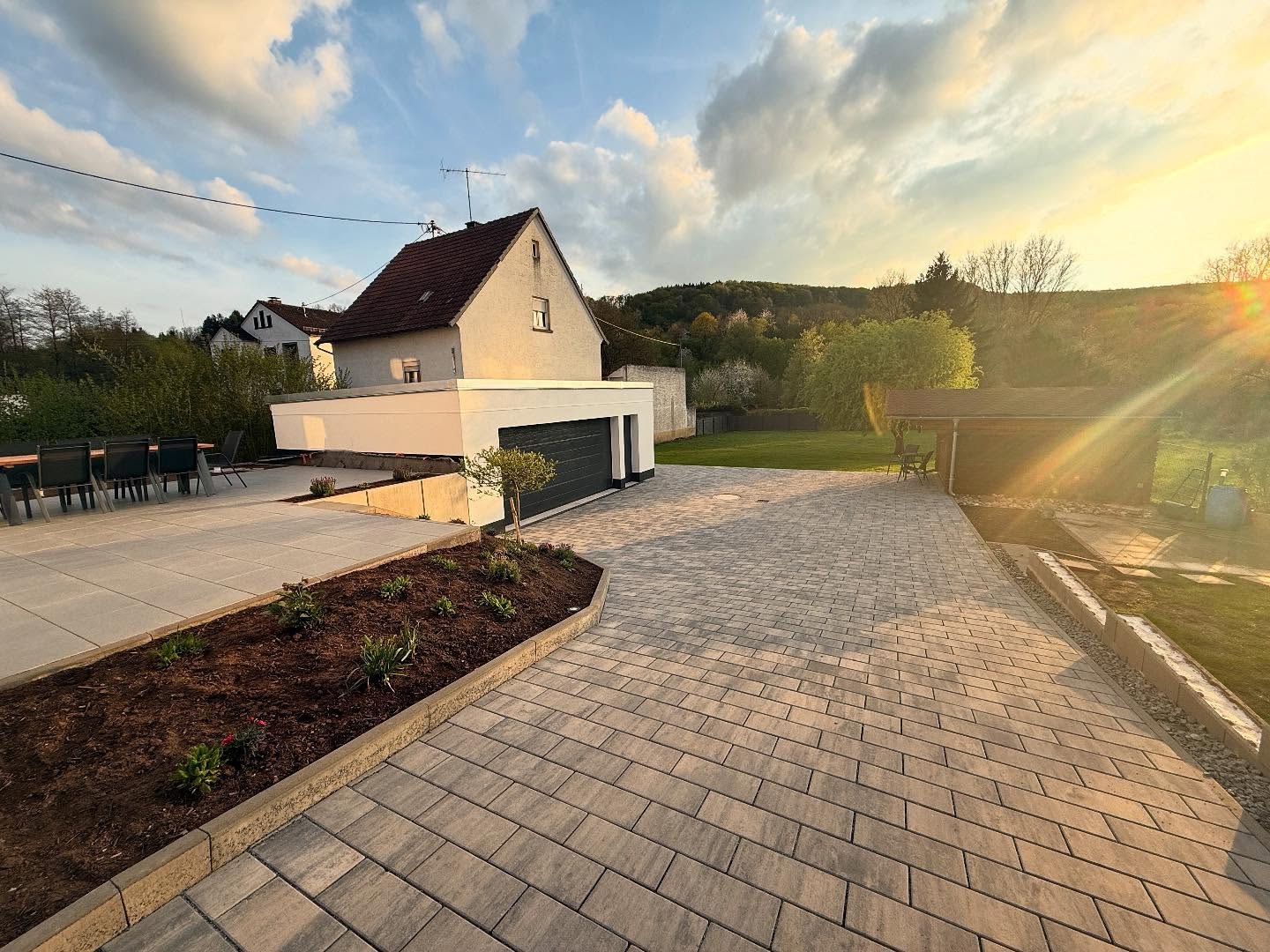 Fertiges Grundstück in der Abendsonne mit gepflastertem Hof und Doppelgarage