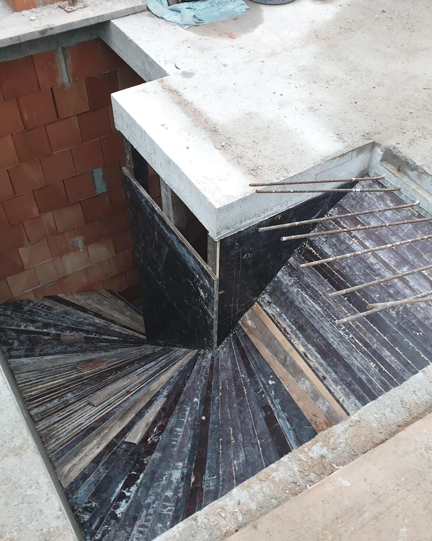 Leere Holzschalung der halbgewendelten Betontreppe von oben, strahlenförmig verlegte Bretter
